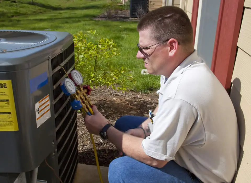 A service technician inspecting a heat pump's reversing valve and defrost controls to ensure efficient heating and cooling performance.