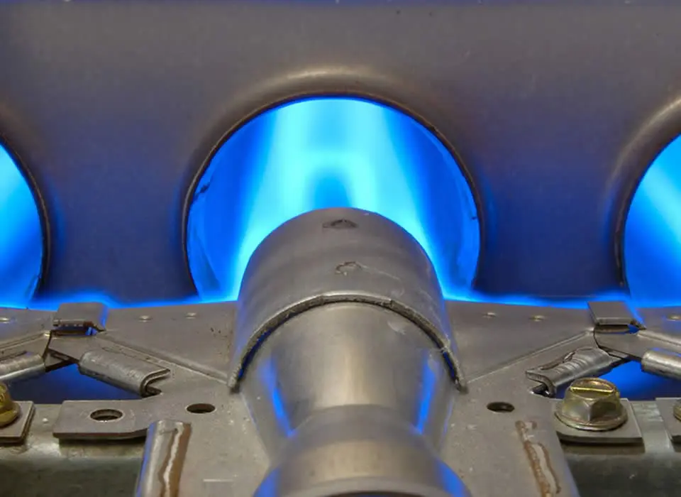 Close-up of gas furnace burners and manifold, illustrating the combustion process in a high-efficiency heating system.