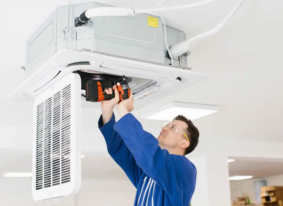 Hvac technician installing air conditioner unit using cordless drill